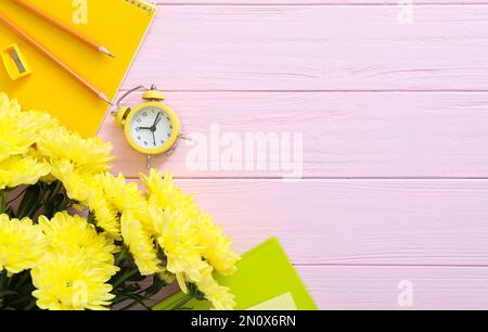 Belles fleurs et papeterie sur fond de bois rose, plat avec espace pour le texte. Journée des enseignants Banque D'Images