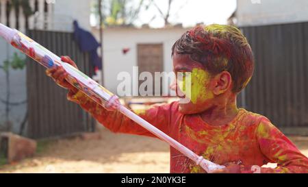 Les enfants indiens vaporent de la couleur avec un pistolet à eau pour célébrer Holi, le festival de couleurs du printemps hindou Banque D'Images
