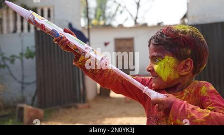 Les enfants indiens vaporent de la couleur avec un pistolet à eau pour célébrer Holi, le festival de couleurs du printemps hindou. Banque D'Images