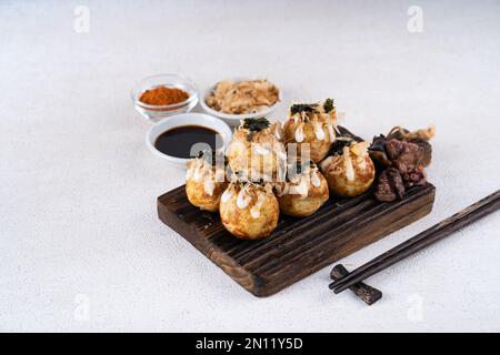 Le takoyaki est une cuisine de rue japonaise contenant du pieuvre, de la saucisse ou du fromage. garnir d'algues et de katsuobushi Banque D'Images