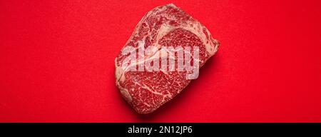 Viande de bœuf non cuite fraîche crue steak de première coupe Ribeye sur fond rouge propre d'en haut, beefsteak concept bannière minimalisme Banque D'Images