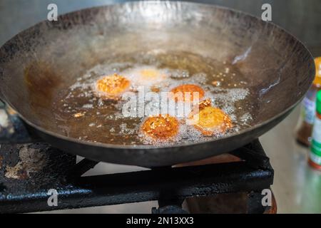 Des boulettes de falafel à friture profonde dans un wok, des huiles de cuisson chaudes bouillant, et des boulettes de falafel ont tourné une couleur dorée Banque D'Images