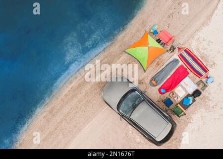 Voiture et équipement de camping sur plage de sable, vue aérienne. Voyage d'été Banque D'Images