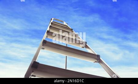 Escabeau en métal contre ciel bleu avec nuages, vue en angle bas. Bannière Banque D'Images