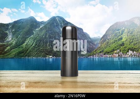 Bureau en bois avec thermos et paysage de montagne en arrière-plan Banque D'Images