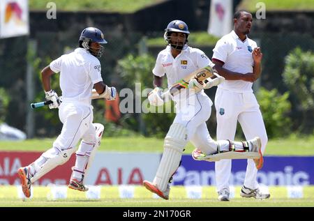 Sri Lankan cricketers Dimuth Karunarathne, left, and Dinesh Chandimal run between the wickets as West Indies' bowler Shannon Gabriel watches during the second day of the first test cricket match against West Indies in Galle, Sri Lanka, Thursday, Oct. 15, 2015. ( AP Photo/ Pamod Nilru )