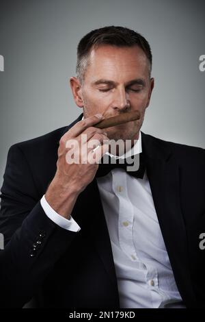 Luxe, richesse et visage de l'homme avec des cigares pour fumer habit sur fond gris pour la classe, la puissance et le succès. Mafia mockup, business gangster et Banque D'Images