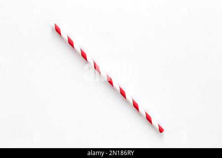 Une paille à boire rouge avec des bandes rouges et blanches sur fond blanc. Banque D'Images