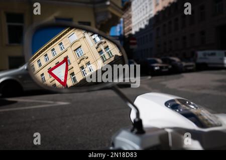 reflet d'un panneau de signalisation routière devant un bâtiment dans le miroir latéral d'une moto debout sur un parking dans une rue de vienne Banque D'Images