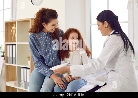 Jolie petite fille de préadolescence avec une maman souriante à la réception dans le bureau de pédiatre à la clinique médicale. Banque D'Images