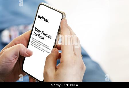 Paris, FR, Jan 2022: Des mains de femmes tenant un téléphone avec le Bereal. application mobile à l'écran. Vue de l'intérieur. BeReal est une application de réseaux sociaux française. Technologie Banque D'Images