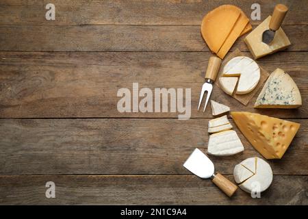 Jeu de différents fromages et couteaux spécialisés et fourchette sur table en bois, plat. Espace pour le texte Banque D'Images