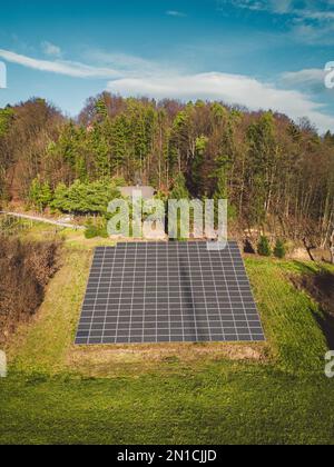 Vue verticale des panneaux solaires empilés sur un côté ensoleillé de la colline dans le côté de la campagne Banque D'Images
