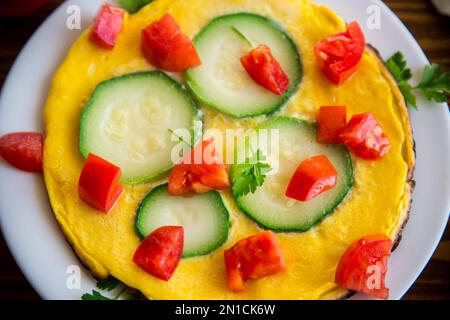Omelette frite avec courgettes, tomates, herbes dans une assiette Banque D'Images
