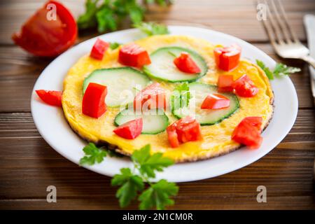Omelette frite avec courgettes, tomates, herbes dans une assiette Banque D'Images