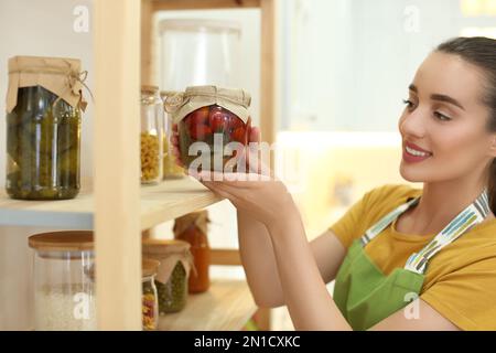 Femme mettant un pot de légumes marinés sur une étagère à l'intérieur Banque D'Images