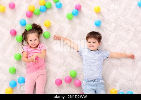 Petits enfants adorables avec jouets au sol à l'intérieur, vue de dessus Banque D'Images