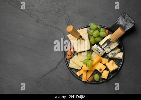 Plateau de fromages avec couteau spécialisé et fourchette sur table noire, vue de dessus. Espace pour le texte Banque D'Images