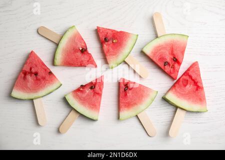 Tranches de pastèque avec bâtonnets de bois sur fond blanc, plat Banque D'Images