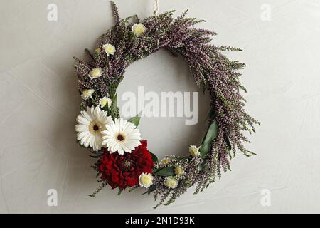 Belle couronne automnale avec fleurs chinées accrochées sur fond gris clair. Espace pour le texte Banque D'Images