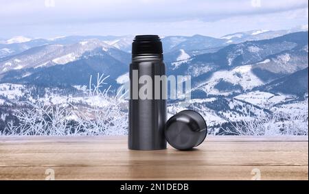 Bureau en bois avec thermos et paysage de montagne en arrière-plan Banque D'Images