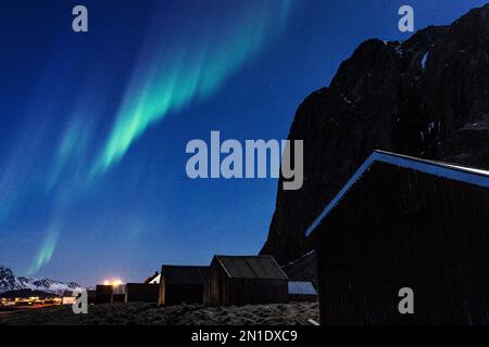 Aurores boréales (Aurora Borealis) dans le ciel étoilé au-dessus des cabines de pêcheurs, Eggum, Vestvagoy, comté de Nordland, îles Lofoten, Norvège Banque D'Images