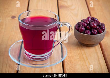 Un verre de thé aux hanches roses et de graines de rosehip sur une table en bois Banque D'Images
