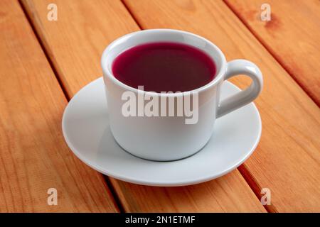 Tasse en verre de délicieux thé aux roses sur une table en bois Banque D'Images