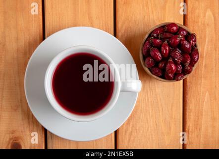 Une tasse de thé de hanche de rose et de graines de hanche de rose sur table en bois, vue de dessus Banque D'Images