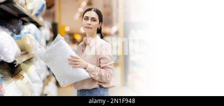 Bannière Web de shopping avec maquette. Portrait de caucasien jeune jolie femme portant des lunettes tient l'oreiller. Textiles domestiques au supermarché. Copier l'espace. Banque D'Images