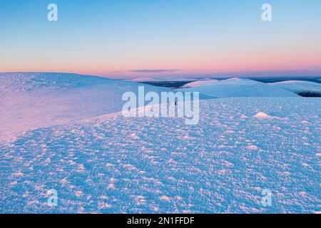 Vue aérienne des randonneurs profitant du ski de fond au coucher du soleil, parc national de Pallas-Yllastunturi, Muonio, Laponie, Finlande, Europe Banque D'Images