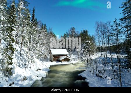 Aurora Borealis (aurores boréales) au-dessus d'un chalet surplombant les rapides de Myllikoski de rivière gelée, Ruka Kuusamo, Laponie, Finlande, Europe Banque D'Images