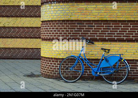 vélo bleu appuyé contre un mur de briques Banque D'Images