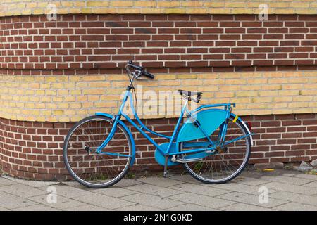 vélo bleu appuyé contre un mur de briques Banque D'Images