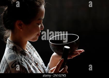 Bol tibétain, femme bouddhiste pratiquant un bol de chant pour la thérapie sonore dans l'atmosphère pour la guérison, la méditation, le yoga et la relaxation, Quang Ninh, Vietn Banque D'Images