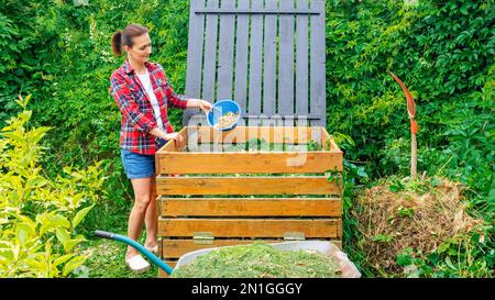 Bac à compost en bois de près. Un jardinier jette des coupures de pelouse et des déchets de cuisine dans un bac à compost de bricolage pour améliorer la fertilité et la structure du sol dans Banque D'Images