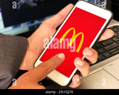 Personne utilisant l'application mobile McDonalds pour commander des aliments, toile de fond éditoriale Banque D'Images