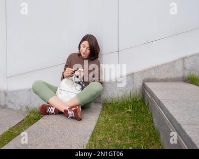 La femme fait du crotcheting à l'extérieur. Loisirs tranquilles de la femme dans le parc urbain. Passe-temps anti-stress. Banque D'Images