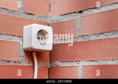 Balcon, prise électrique extérieure sur un mur de briques. Source d'alimentation dans la maison de près Banque D'Images