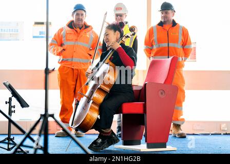 Su-a Lee, le principal violoncelliste du Scottish Chamber Orchestra, joue auprès d'un public de travailleurs de la construction lors d'une conférence de presse marquant le premier jour de travail pour nettoyer le site près de St Andrew Square, à Édimbourg, en amont de la construction du Dunard Centre, la nouvelle salle de concert de classe mondiale de la ville. Date de la photo: Lundi 6 février 2023. Banque D'Images