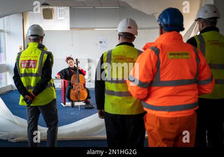 Su-a Lee, le principal violoncelliste du Scottish Chamber Orchestra, joue auprès d'un public de travailleurs de la construction lors d'une conférence de presse marquant le premier jour de travail pour nettoyer le site près de St Andrew Square, à Édimbourg, en amont de la construction du Dunard Centre, la nouvelle salle de concert de classe mondiale de la ville. Date de la photo: Lundi 6 février 2023. Banque D'Images