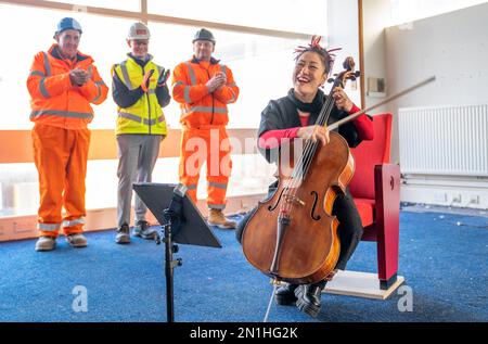 Su-a Lee, le principal violoncelliste du Scottish Chamber Orchestra, joue auprès d'un public de travailleurs de la construction lors d'une conférence de presse marquant le premier jour de travail pour nettoyer le site près de St Andrew Square, à Édimbourg, en amont de la construction du Dunard Centre, la nouvelle salle de concert de classe mondiale de la ville. Date de la photo: Lundi 6 février 2023. Banque D'Images