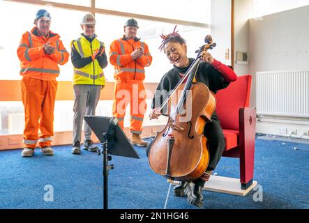 Su-a Lee, le principal violoncelliste du Scottish Chamber Orchestra, joue auprès d'un public de travailleurs de la construction lors d'une conférence de presse marquant le premier jour de travail pour nettoyer le site près de St Andrew Square, à Édimbourg, en amont de la construction du Dunard Centre, la nouvelle salle de concert de classe mondiale de la ville. Date de la photo: Lundi 6 février 2023. Banque D'Images