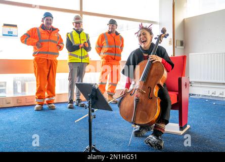 Su-a Lee, le principal violoncelliste du Scottish Chamber Orchestra, joue auprès d'un public de travailleurs de la construction lors d'une conférence de presse marquant le premier jour de travail pour nettoyer le site près de St Andrew Square, à Édimbourg, en amont de la construction du Dunard Centre, la nouvelle salle de concert de classe mondiale de la ville. Date de la photo: Lundi 6 février 2023. Banque D'Images