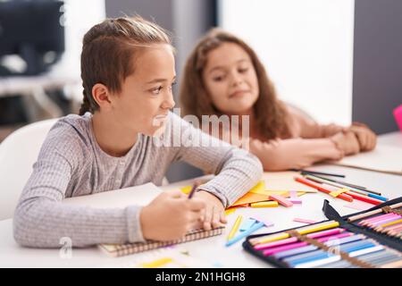 Deux enfants sont assis sur une table et dessinant sur un carnet de notes en classe Banque D'Images