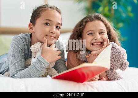 Deux enfants lisant un livre d'histoire allongé sur le lit dans la chambre Banque D'Images