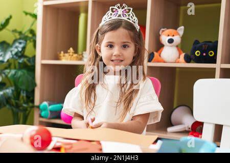 Adorable fille blonde étudiante portant le papier de coupe de la couronne de princesse à la maternelle Banque D'Images