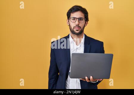 Beau latin homme travaillant à l'aide d'un ordinateur portable regardant endormi et fatigué, épuisé pour la fatigue et la gueule de bois, les yeux paresseux le matin. Banque D'Images