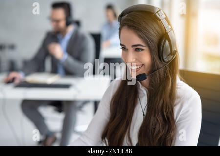 Portrait en gros plan d'une jeune femme très attirante de l'assistance clientèle avec un micro-casque travaillant dans un centre d'appels Banque D'Images