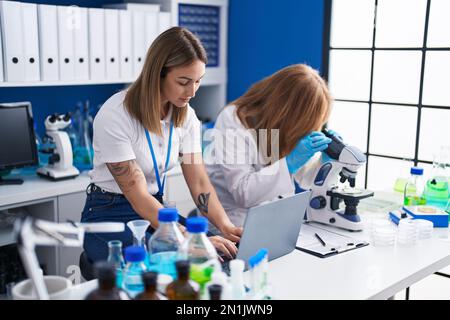 Mère et fille scientifiques utilisant un ordinateur portable et un microscope au laboratoire Banque D'Images